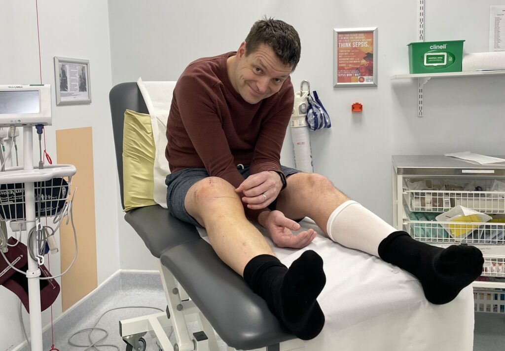 Geoff on a hospital bed having his wounds and stitches checked